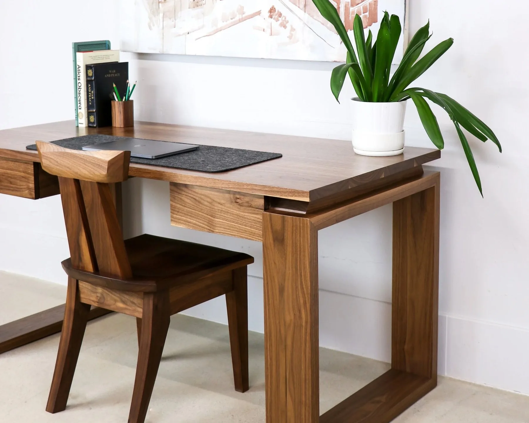 A walnut desk and chair built by Sustar Woodworks, set against a white wall.
